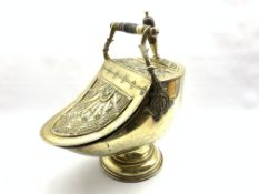 Victorian brass helmet shaped coal scuttle having embossed decoration with turned wooden handle and