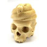 Late 19th century Japanese carved ivory okimono in the form of a skull beneath a coiled snake with a