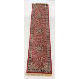 Persian design red ground runner rug, with three medallions on red field, 78cm x 310cm