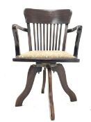 Early 20th century walnut swivel office armchair, with comb back and upholstered seat raised on spl