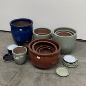 Twelve glazed terracotta plant pots, (D45cm Max) and twelve plant pot plates of varying size and co