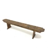 19th century solid pine bench raised on panel end supports, L213cm