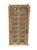 Pair northern Indian teak and metal bound doors, with carved detail and decorative brass studding,