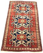 Caucasian style rug, with triple geometric medallion on red field, 112cm x 197cm