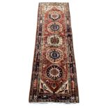 Unusual Persian runner rug, red ground field with five medallions and decorated with stylised flower