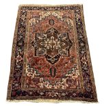Persian Heriz red ground rug, geometric medallion on red field, decorated with stylised flower heads