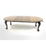 Early 20th century mahogany extending dining table, the oval top with floral edging over acanthus ca