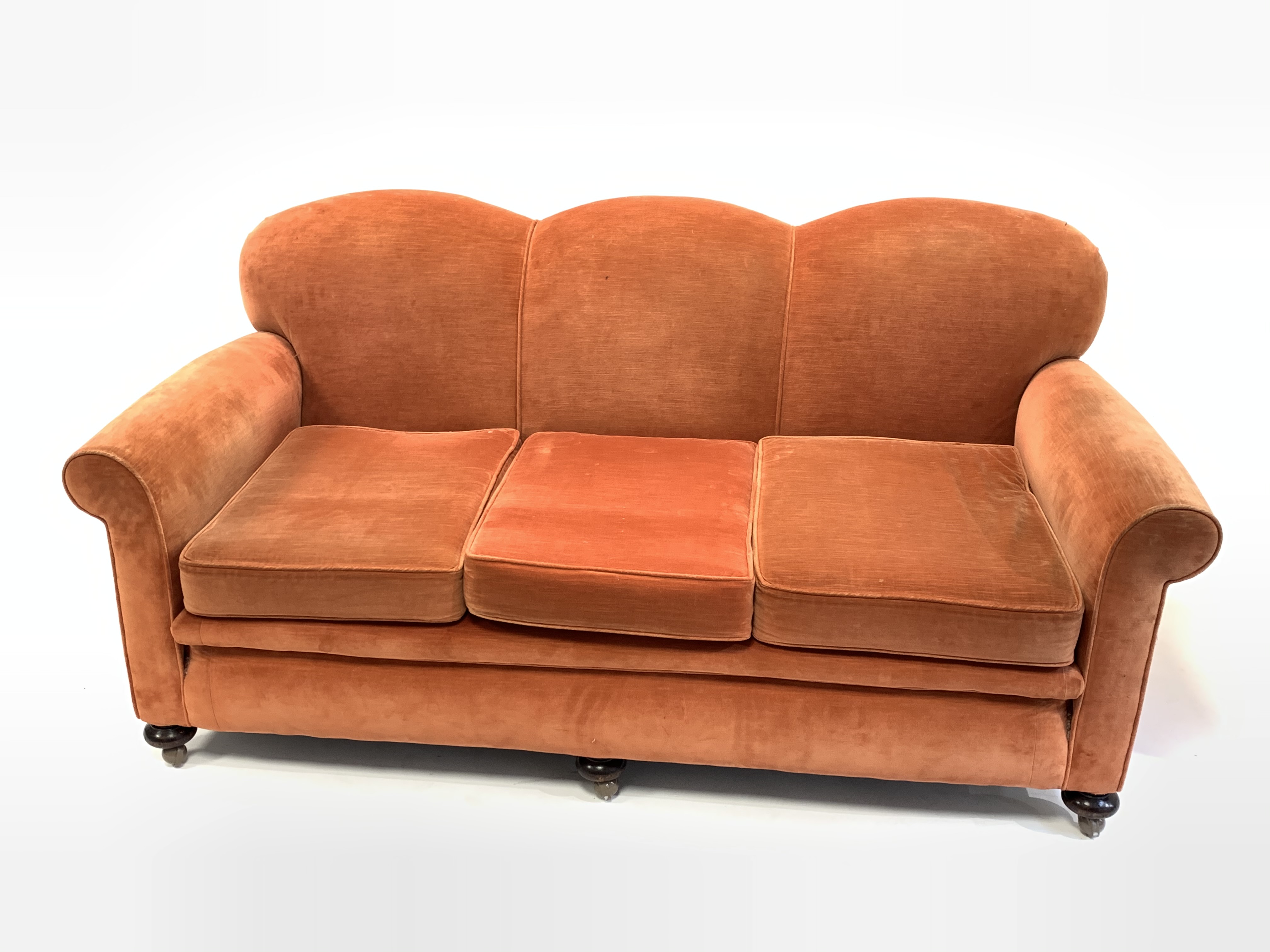 Early to mid 20th century three seat sofa, with serpentine back over loose cushions, raised on turne