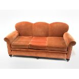 Early to mid 20th century three seat sofa, with serpentine back over loose cushions, raised on turne
