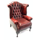 20th century wingback armchair, upholstered in deep buttoned and studded oxblood leather, raised on