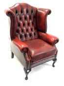 20th century wingback armchair, upholstered in deep buttoned and studded oxblood leather, raised on