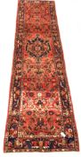 Persian Hamadan runner rug, central medallion on red field, enclosed by guarded border, 370cm x 105c