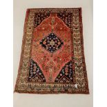 Persian red ground rug, with lozenge medallion on field decorated with stylised geometric floral des