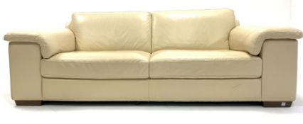 Contemporary three seat sofa, upholstered in cream faux leather, raised on walnut block supports, W2
