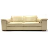 Contemporary three seat sofa, upholstered in cream faux leather, raised on walnut block supports, W2