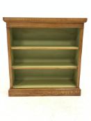 Figured oak open bookcase, cross banded and inlaid top over two adjustable shelves, plinth base, W96