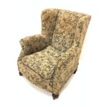 Victorian wingback upholstered armchair, with loose cushion, raised on walnut bun front supports and
