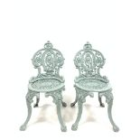 Pair of Victorian style cast iron garden chairs raised on four splayed supports with mask decoration