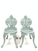 Pair of Victorian style cast iron garden chairs raised on four splayed supports with mask decoration