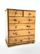 Modern polished pine chest fitted with two short and four long drawers, raised on compressed bun sup