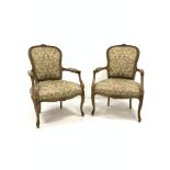 Pair of French style beech upholstered open salon armchairs, floral carved cresting rail, incised an