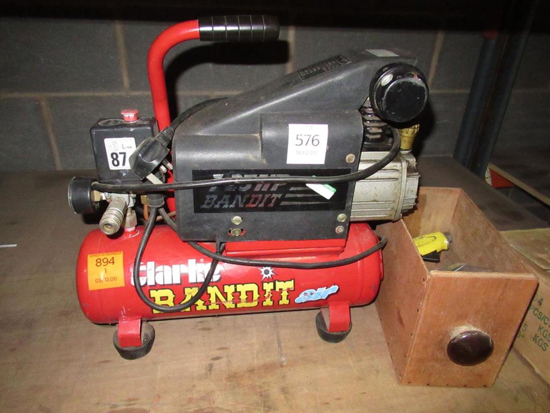 A Clarke Bandit Air Compressor with a box of assorted gauges and connectors