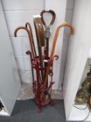 Red painted metal stand with four walking sticks & a shooting stick