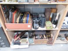 Two shelves of picture frames, bottle cases/boxes, tins etc