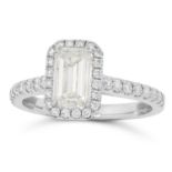 A DIAMOND SOLITAIRE RING set with an emerald cut diamond of 1.21 carats in a halo of round cut