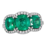 AN EMERALD AND DIAMOND RING set with three cushion cut emeralds totalling 3.0-3.5 carats, in a