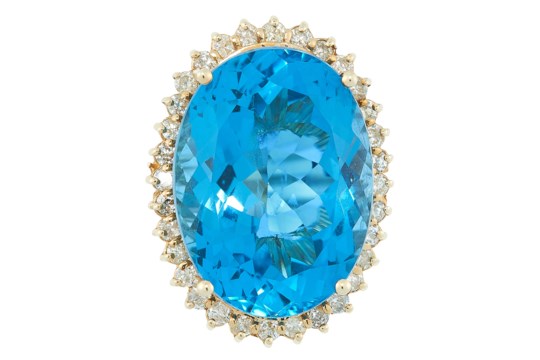 A TOPAZ AND DIAMOND CLUSTER RING set with an oval cut topaz of 27.8 carats, in a border of round cut