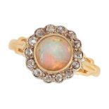 AN OPAL AND DIAMOND CLUSTER RING in high carat yellow gold, set with a cabochon opal in a border