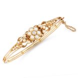 AN ANTIQUE DIAMOND AND PEARL BANGLE in yellow gold, set with a central old cut diamond within a