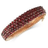 AN ANTIQUE GARNET BANGLE the tapering body set with four rows of rose cut garnets, unmarked, inner