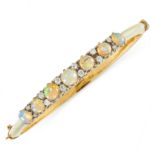 AN ANTIQUE OPAL AND DIAMOND BANGLE in yellow gold, set with a row of seven graduated cabochon