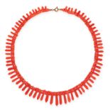 AN ANTIQUE CORAL COLLAR NECKLACE designed as a fringe of graduated polished coral batons