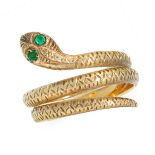 AN EMERALD SNAKE DRESS RING in high carat yellow gold, designed as the body of a snake coiled around