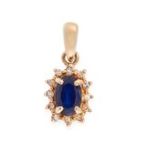 A SAPPHIRE AND DIAMOND CLUSTER PENDANT in yellow gold, set with an oval cut sapphire in a border