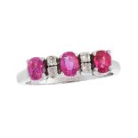 A RUBY AND DIAMOND DRESS RING set with a trio of graduated oval cut rubies punctuated by pairs of