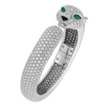 A DIAMOND AND EMERALD PANTHER BANGLE in 18ct white gold, designed as a coiling panther, set all over