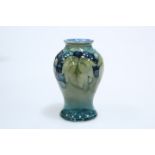 A MOORCROFT POTTERY CELADON LEAF AND BERRY PATTERN VASE