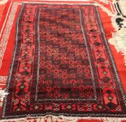 A BALOUCH RUG, with a red ground, circa 1940. 205cm by 105cm