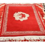 A CHINESE RUG, centred by a dragon, on a red ground. 204cm by 122cm