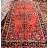 A LILIAN CARPET, with large central motif on a red ground, dark blue border