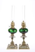 A PAIR OF LATE VICTORIAN BRASS AND GREEN GLASS OIL LAMPS