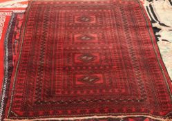 A BALOUCH RUG, with four centre reserves and a red ground, circa 1950