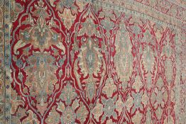 A LARGE KERMAN CARPET, with a red ground. Approx. 630cm by 389cm