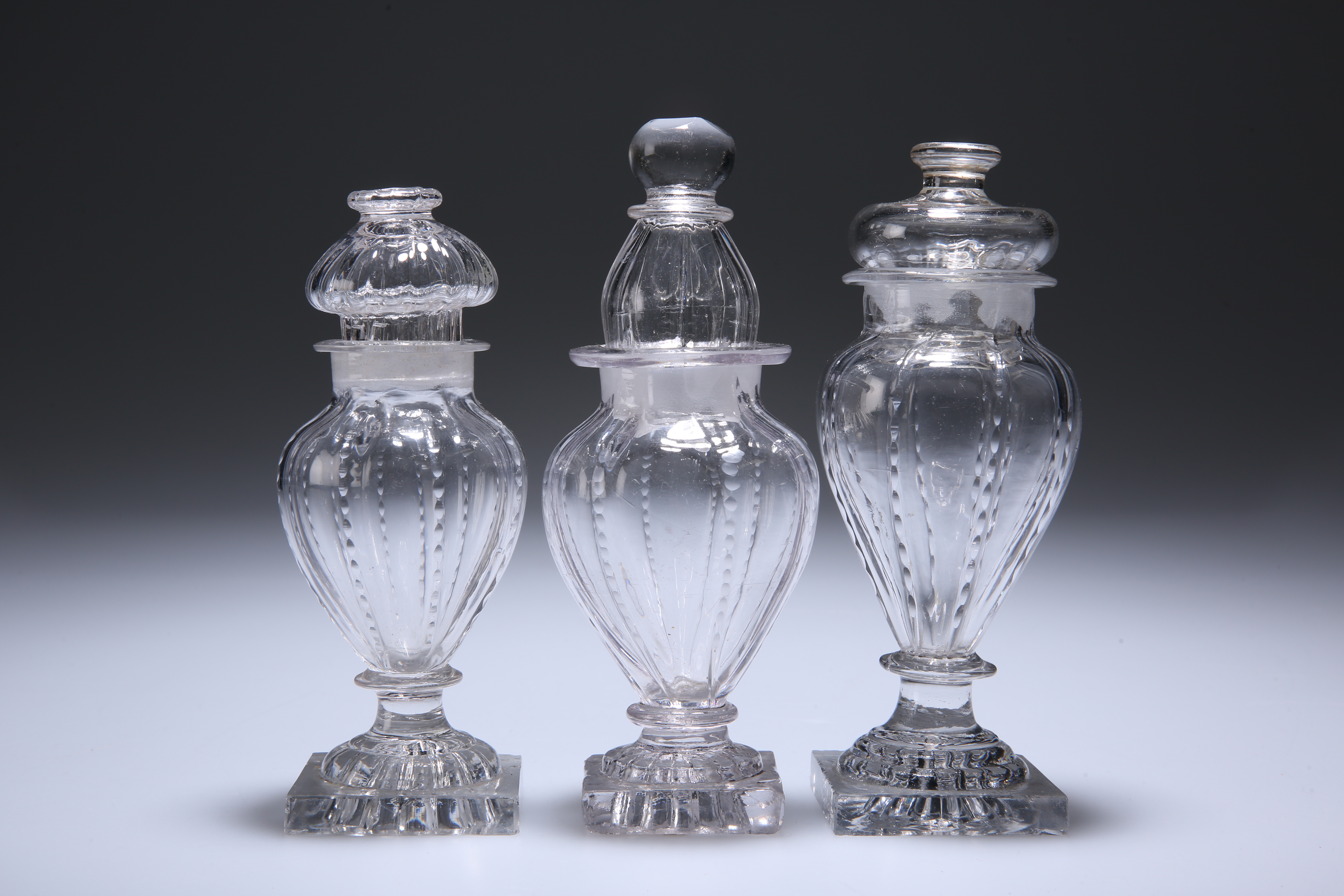 THREE ENGLISH GLASS CONDIMENT BOTTLES AND STOPPERS, CIRCA 1800