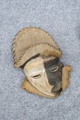TRIBAL: A MASK, carved with off-set mouth and twisted nose