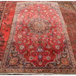 A MASHAD CARPET, with central medallion eight outer petals, on a red ground